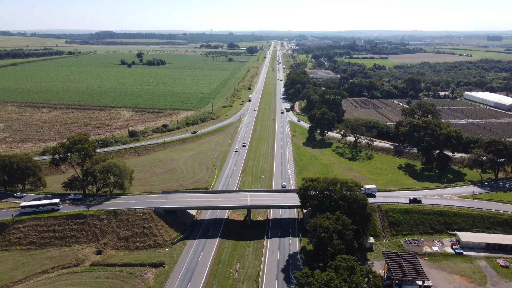 Rodovia duplicada com viaduto e campos cultivados